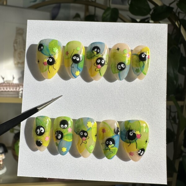 Soot sprites on a dreamy watercolor backdrop of yellow, lime, teal, and peach. Each sprite features wide eyes, squiggly limbs, and pastel star candy. The design has a glossy finish with soft, ethereal color wash and translucent jelly tones, accented with fine detail lines and black sparkles.