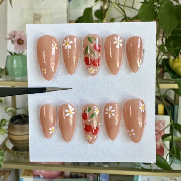 A little retro, a little romantic, and just the right amount of playful—Cherry on Top is the summertime sweetheart of nail sets. Juicy red cherry decals and tiny white daisies bloom across a creamy nude base, creating a soft-yet-vibrant vibe that’s equal parts sweet and chic. It’s the perfect finishing touch to any outfit, rain or shine.