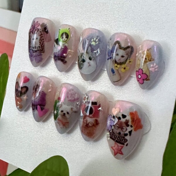 Press-on nails with half-cat and half-dog designs in pastel tones. Short almond press-on nail set with mismatched hands: one hand features pastel-colored cat decals and playful feline designs, while the other hand showcases whimsical dog illustrations. The set is fun, soft-toned, and perfect for pet lovers.